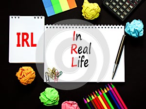 IRL in real life symbol. Concept words IRL in real life on white paper on white note on a beautiful black background. Black