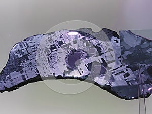 Iron alien meteorite with Widmanstatten pattern on light