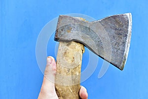 Iron axe with wooden handle in hand on a blue background