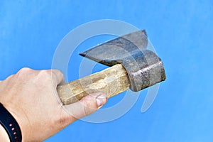 Iron axe with wooden handle in hand on a blue background