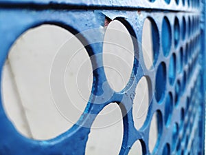 Iron blue fence with round holes, peeling paint, and under it rust. Abstract background