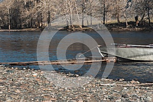 Iron boat is tied with rope to wooden pier. Crossing spring river. Evacuation of people in high water