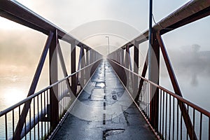 Iron bridge over the river in a misty morning