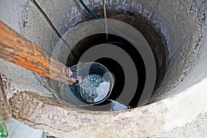 Iron bucket with water at the depth of a round well