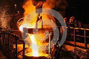 Iron casting. Molten metal pouring from blast furnace into ladle. Steel production in foundry workshop. Metallurgical