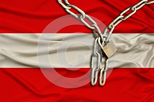 Iron chain and castle on Austria`s silk national flag with beautiful folds, the concept of a ban on tourism, political repression