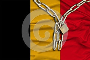 Iron chain and castle on the silk national flag of Belgium with beautiful folds, the concept of a ban on tourism, political