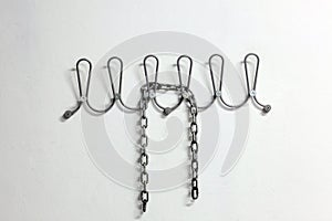 Iron chain on a clothes hanger on a white wall with copy space