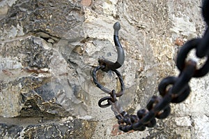 Iron chain with a hook on the wall of an ancient castle in Italy