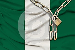 Iron chain and lock on the Nigeria silk national flag with beautiful folds, the concept of a ban on tourism, political repression