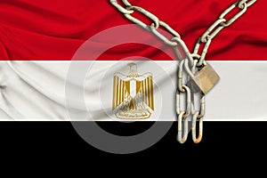 Iron chain and lock on the silk national flag of Egypt with beautiful folds, the concept of a ban on tourism, political repression