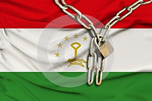 Iron chain and lock on silk national flag of kingdom of tajikistan with beautiful folds, the concept of a ban on tourism,