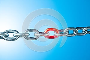 Iron chain with red link on blue background with copy space.