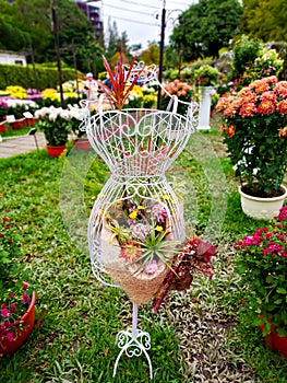 An iron clothes hanger placed in the garden, decorated with beautiful flowers, garden landscaping.