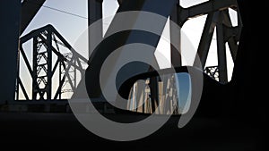 Iron construction of bridge against blue sky with white clouds. Driving on bridge, crossing steel beams.