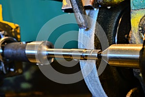 The iron cylindrical part is mounted on a grinding machine, close-up.