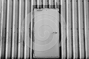 Iron door on corrugated metal sheet, black and white photo