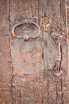 Iron door knocker, handle and lock, on a 1500's year old wood door, in Italy