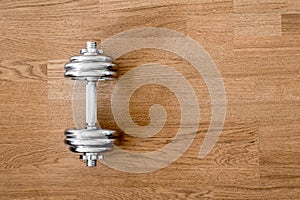 Iron dumbbell on a wooden hard floor background in natural lighting.