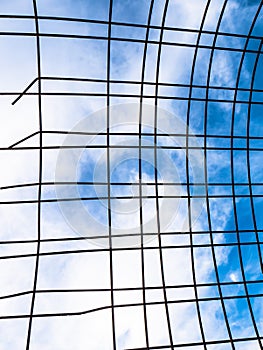 Iron fence made up of rusty metal bars outdoors with a blue sky in the background