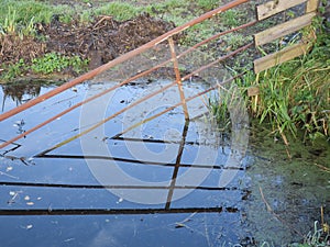 Iron fence and it`s reflection in a ditch