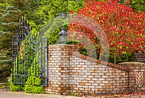 Iron front gate of a luxury home. Wrought iron white gate and brick pillar