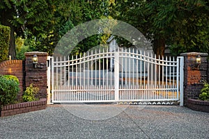 Iron front gate of a luxury home. Wrought iron white gate and brick pillar