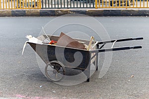 iron garbage carrier filled with garages at tarmac road at morning