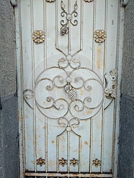 Iron gate with ornamental wine grape brunch, architectural detail and symbol of viniculture