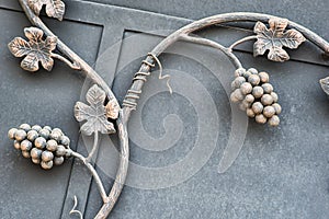 Iron gate with ornamental wine grape brunch, architectural detail and symbol of viniculture with text