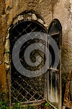 Iron grating behind the door in old stone wall