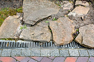 Iron grating line of the drainage system of the pedestrian sidewalk made of stone.