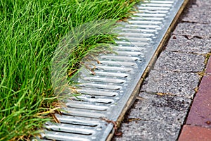 An iron gutter with grate to the drainage system.