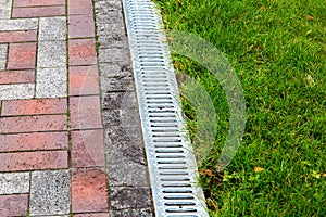 An iron gutter with grate to the drainage system.