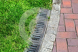 iron gutter with grate to the drainage system on the side of the pedestrian walkway.