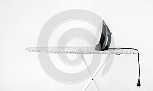 Iron on ironing board against white wall background