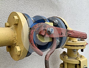 Iron lever on the gas pipe. Pipeline gas separation valve. Yellow-blue gas pipe with damper