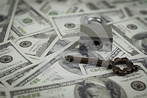 Iron lock key on the group of money stack of 100 US dollars banknote a lot of the background texture, top view
