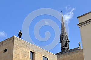 Iron man statue with Exeter College Chapel spike behind it in Oxford, UK