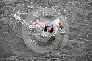Iron man swimmer in cap and wetsuit breathing performing butterfly stroke