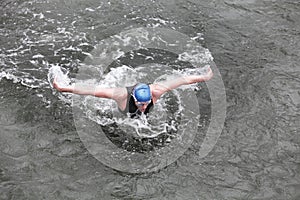 Iron man swimmer in cap and wetsuit breathing performing butterfly stroke