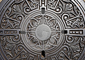 Iron manhole cover featuring intricate patterns and symmetrical