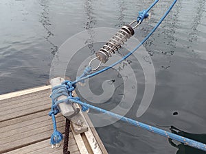 Iron mooring with blue ropes and rope tensioner. Nautical lines close up. Mooring yacht rope with a knotted end tied around a