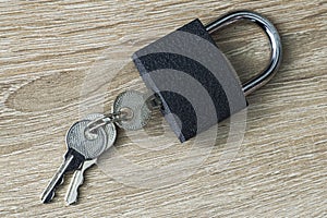 Iron padlock with keys in the keyhole on a wooden surface concept prohibition security restriction