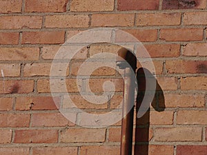 An iron pipe in front of a brick wall