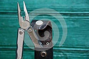 Iron pliers in a leather case on a green background