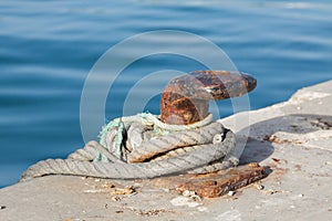 Iron pole for mooring of ships at pier, old rusty iron bollard on a pier on the coast of Andalucia, Spain