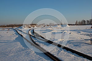 Iron rails the path for the train in the direction of freight covered with snow at the railway crossing in the winter