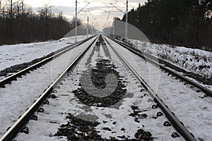 Iron rails of a railway near a train station of a railroad in winter with snow