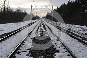 Iron rails of a railway near a train station of a railroad in winter with snow